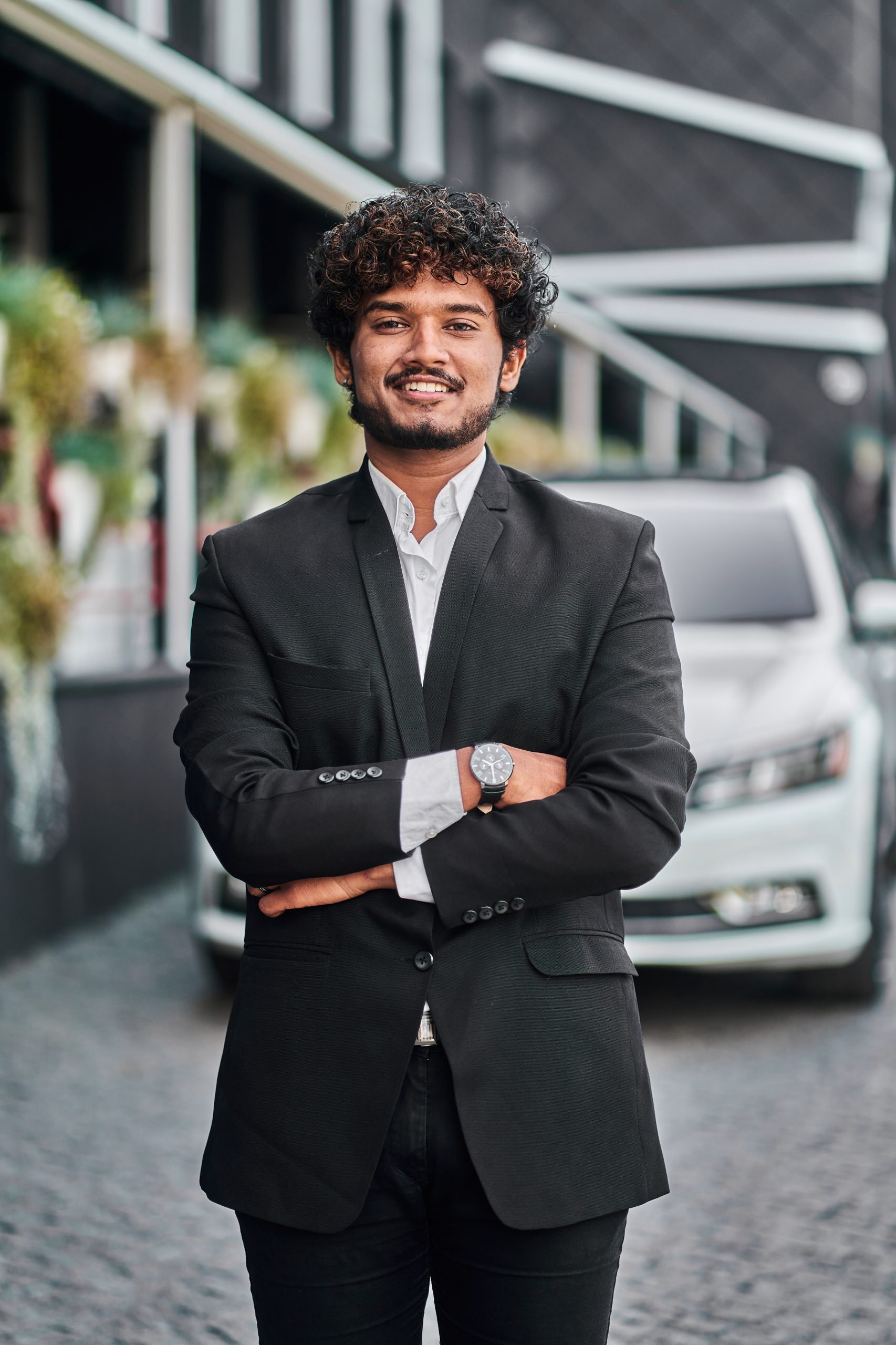 indian businessman in the background of his white car